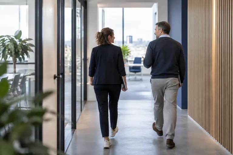 Medewerker loopt door een kantoorgang, op weg naar een volgende stap in de re-integratie