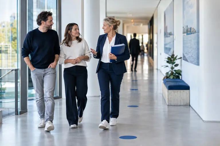 Drie professionals lopen pratend door een kantoorgang