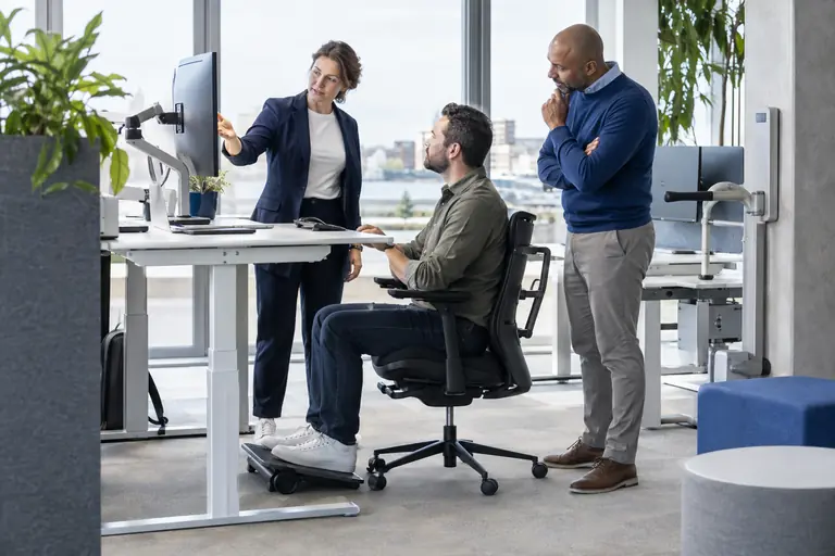 Adviseur bespreekt een in hoogte verstelbaar bureau met een medewerker